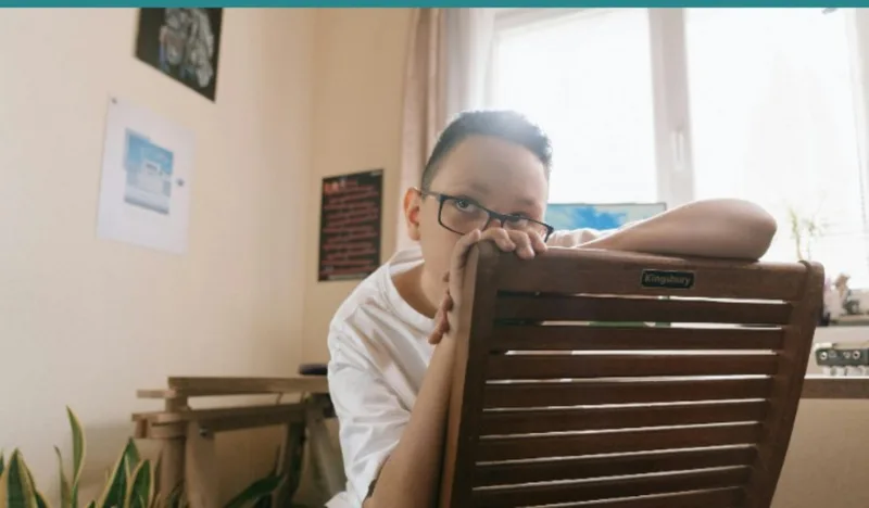 Restless child at home during fall break looking out window