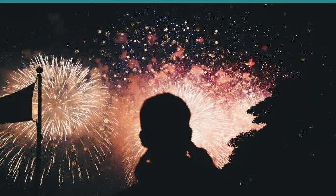 Child's silhouette watching fireworks at night