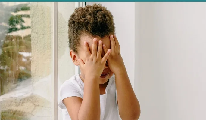 Child covering their face with both hands