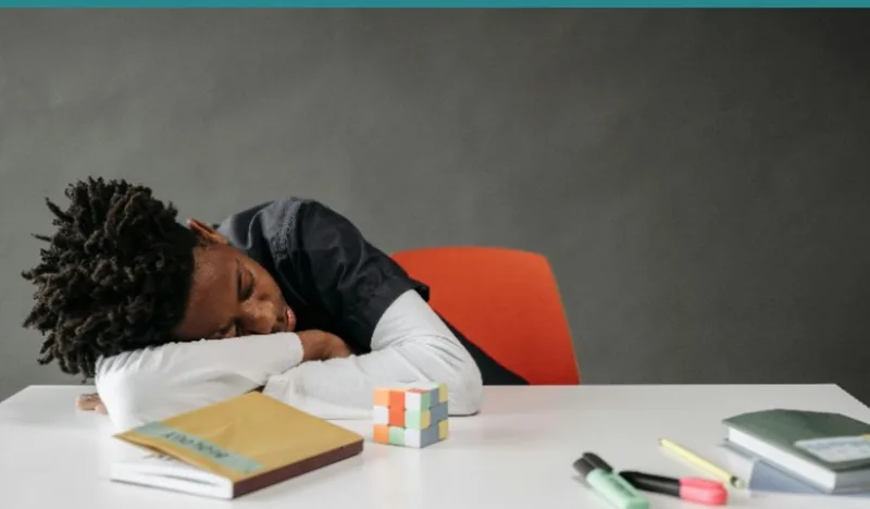 Tired child at desk with homework in the evening