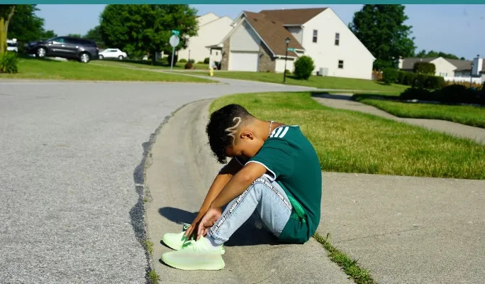 Child sitting quietly, appearing tired after a long day